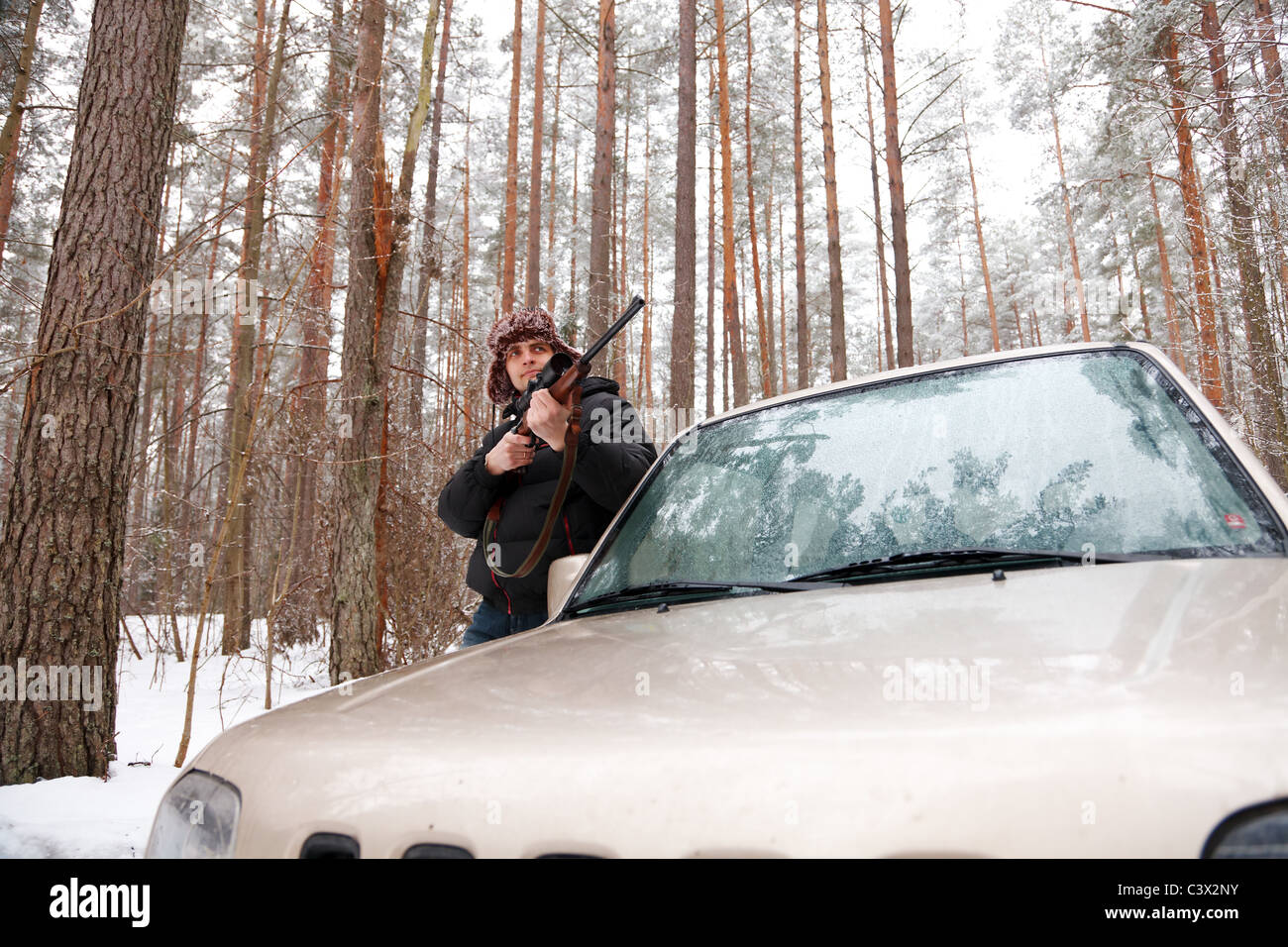 Man with sniper rifle and jeep in winter forest. Wide-angle shot. Stock Photo