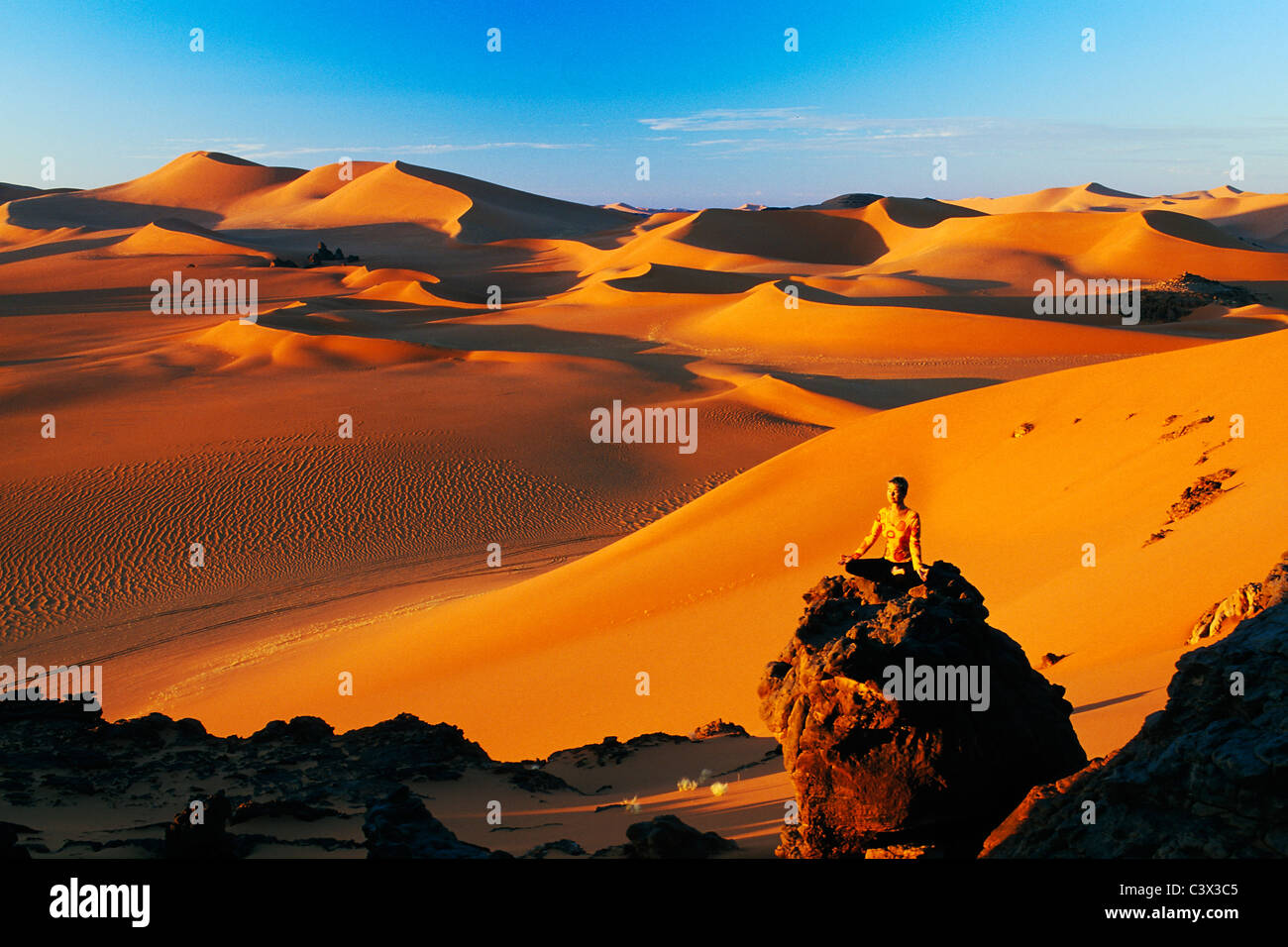 Algeria, Djanet. Sand dunes and rocks. Woman meditating. Sahara Desert. Stock Photo