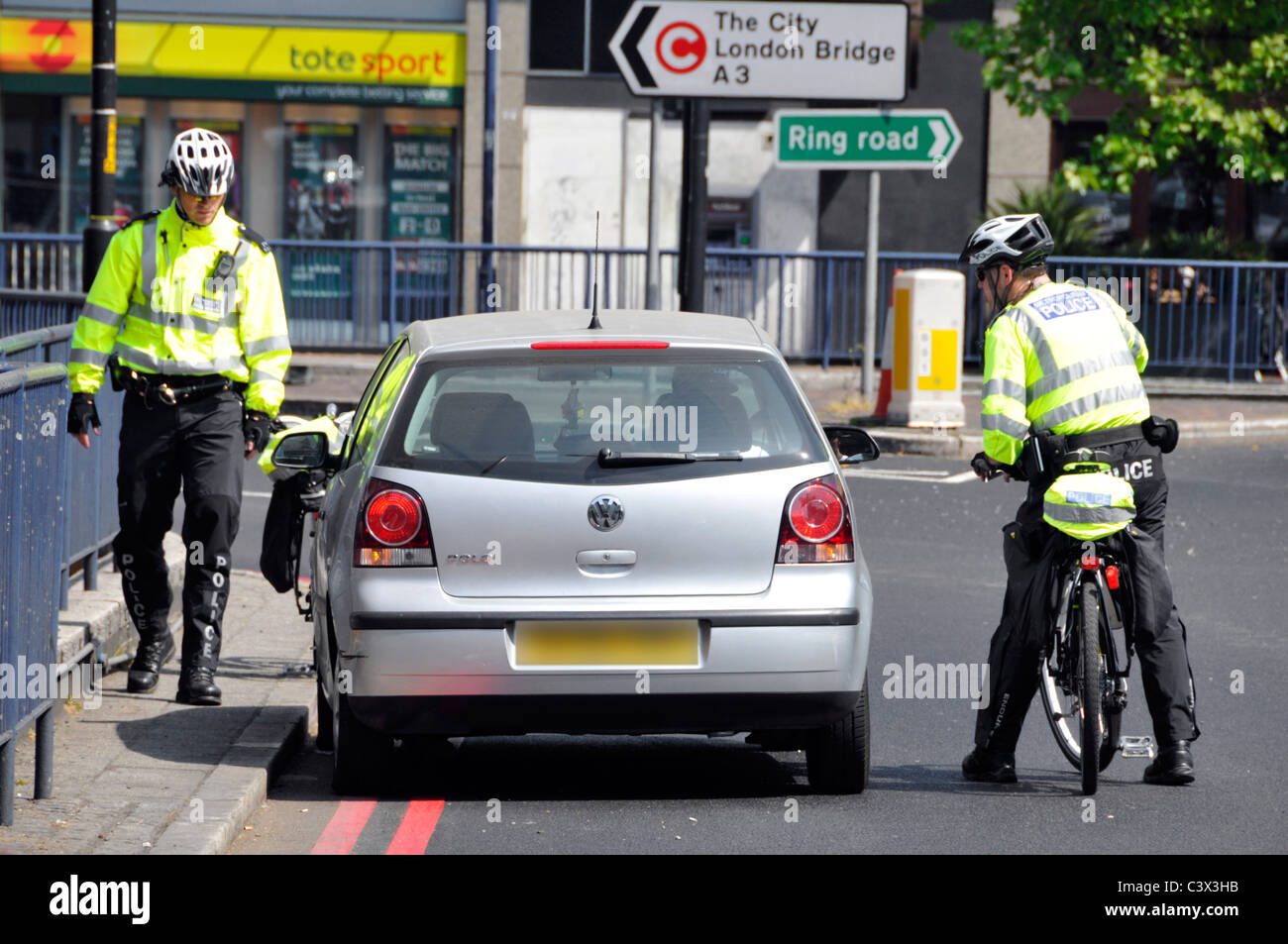 Two police officers on pedal bikes pull over a motorist Stock Photo