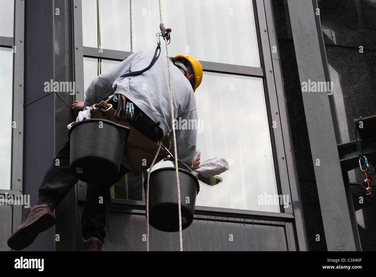 Steeplejack washes office facade. Stock Photo