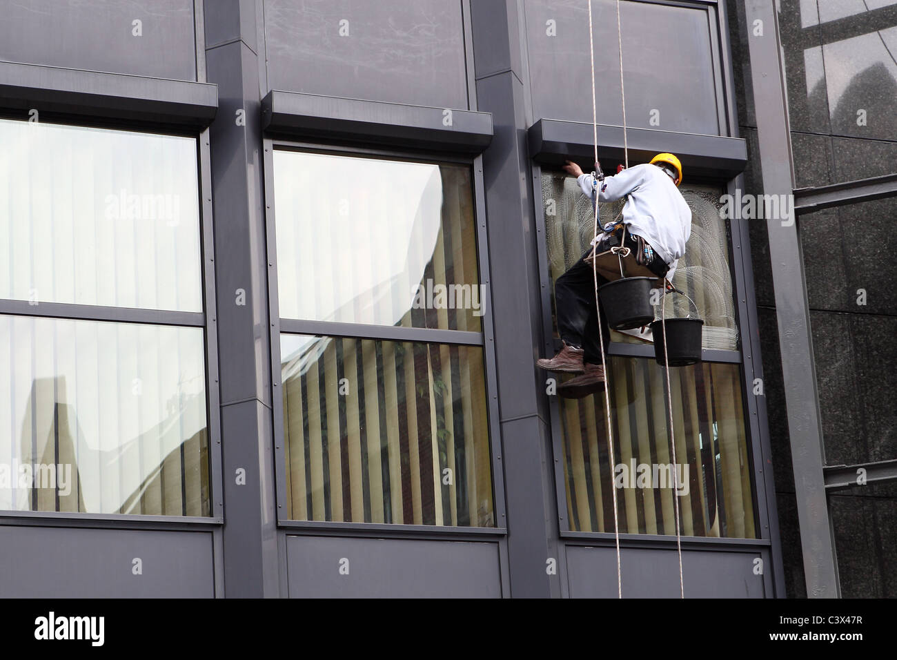 Steeplejack washes office facade. Stock Photo