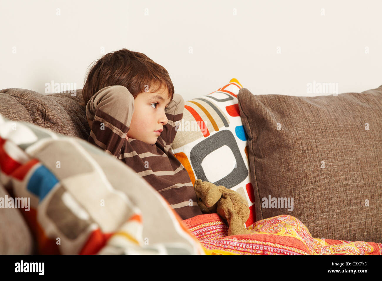 Boy sitting on sofa staring at tv Stock Photo - Alamy