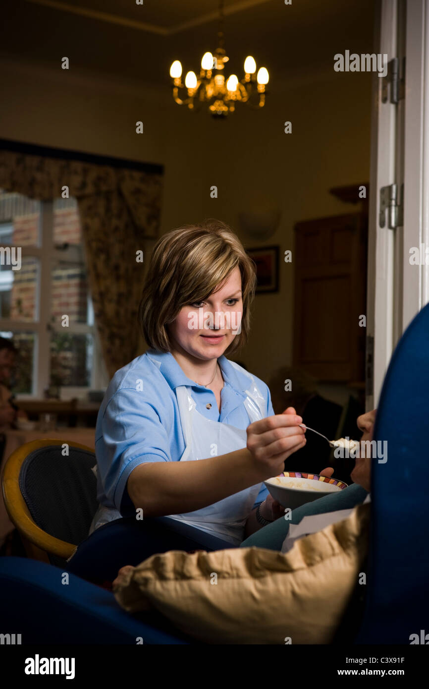 Care worker feeds lunch to a resident in a private nursing home for the elderly Stock Photo