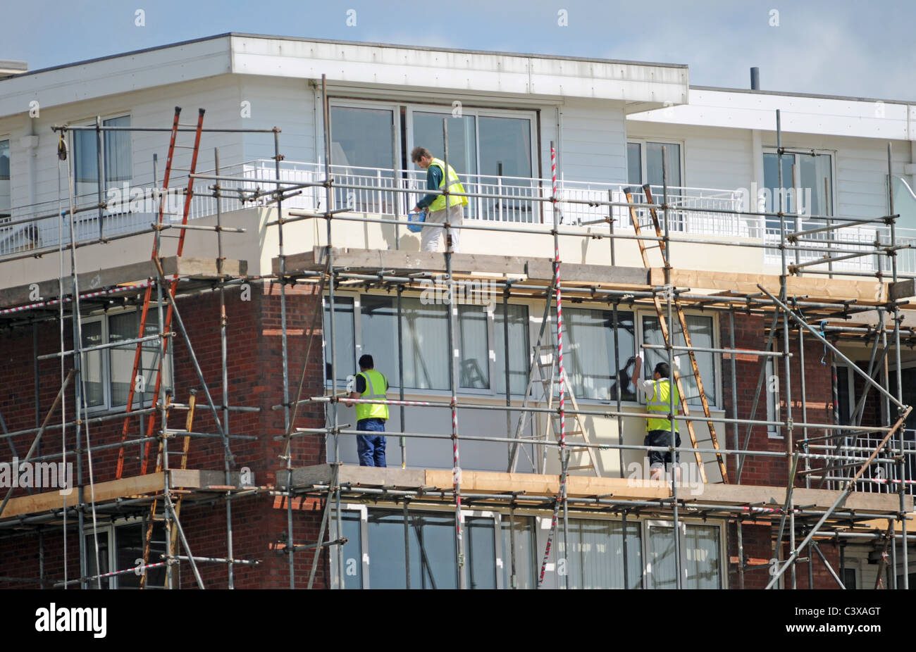 Builders working on scaffolding beside a block of flats UK Stock Photo