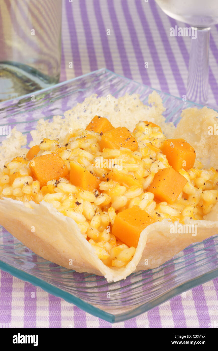 Cheese basket filled with risotto and pumpkin over a glass dish. Stock Photo