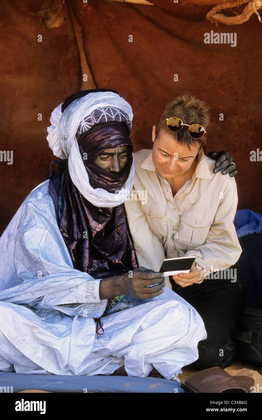 Mali, Anderamboukane, Touareg man in festival dress looking at polaroid photo with woman tourist. Stock Photo