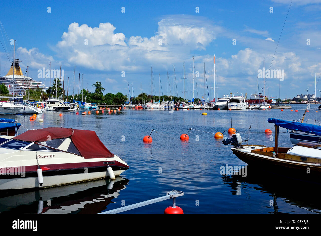 A view over small pleasure boats moored in a pleasant waterfront towards a cruise ship berthed at Langelinie pier, Copenhagen Stock Photo