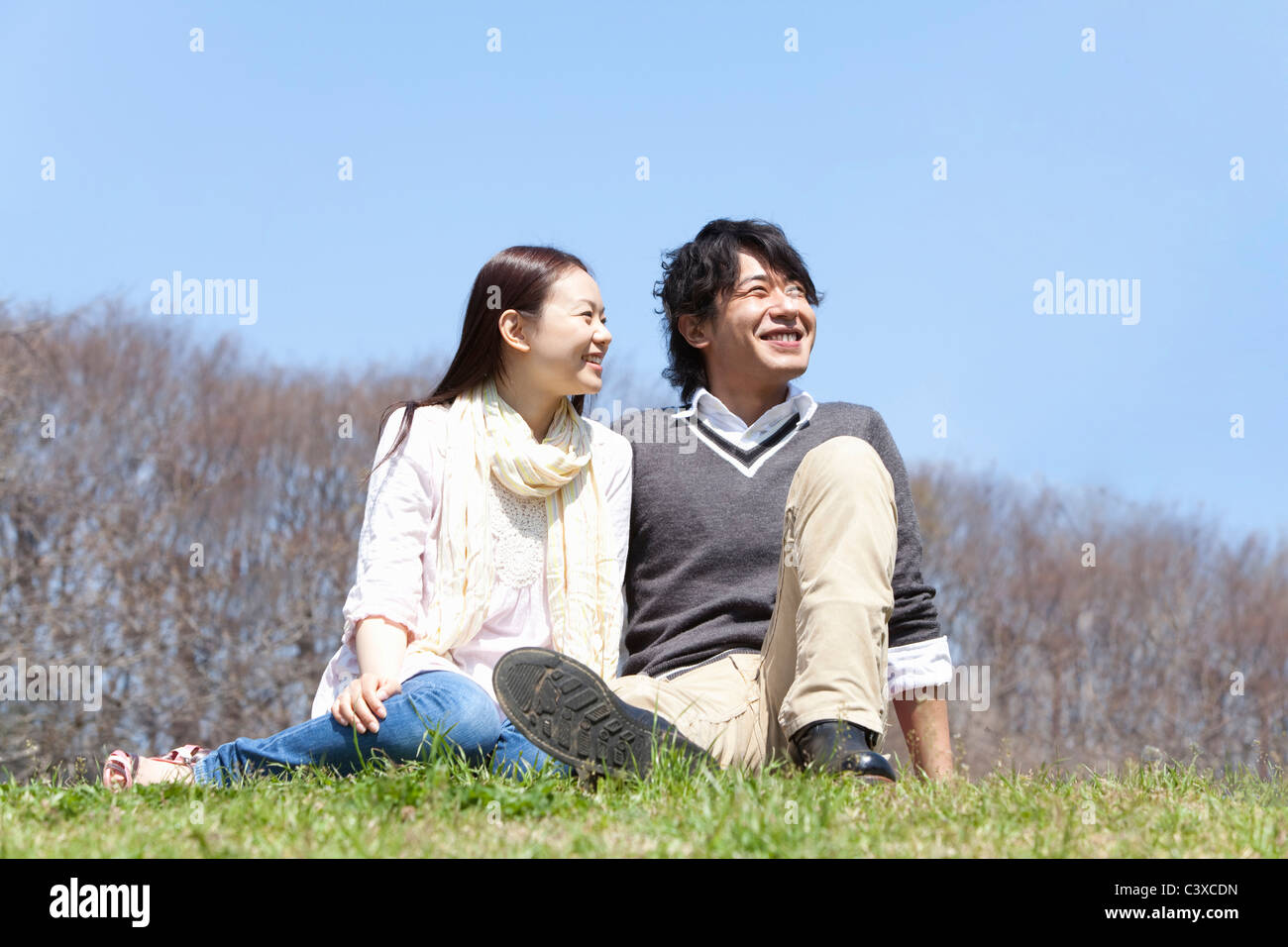 Young Couple Sitting on Lawn Stock Photo - Alamy