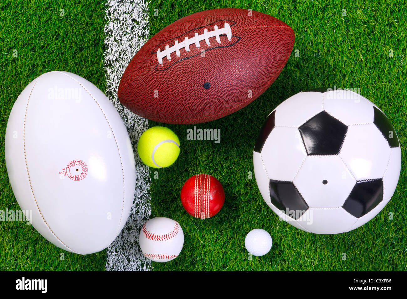 Photo of various sports balls on a grass next to the white line, shot from above. Stock Photo