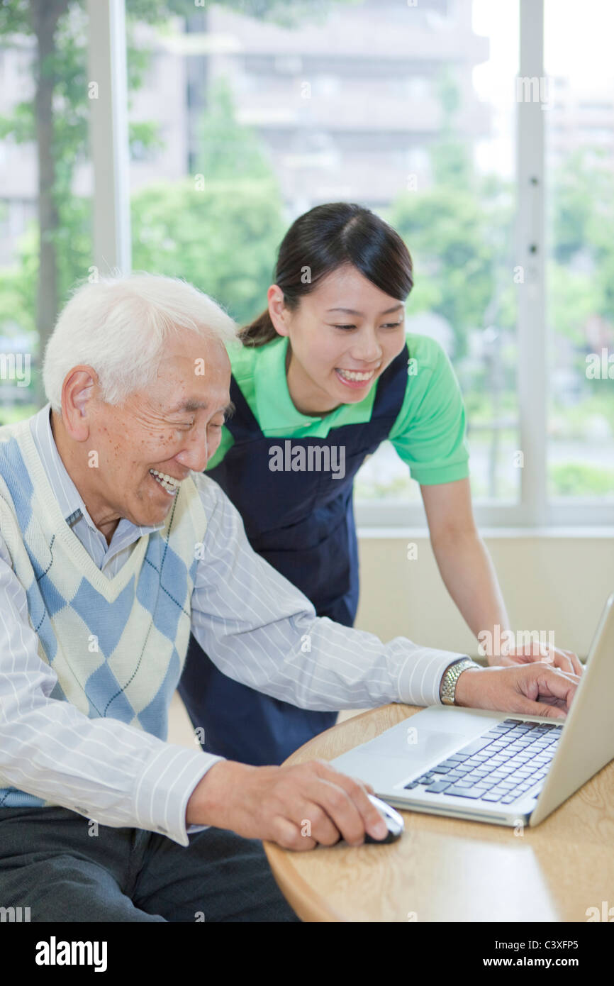 Senior man and nurse using a laptop, Kanagawa Prefecture, Honshu, Japan Stock Photo
