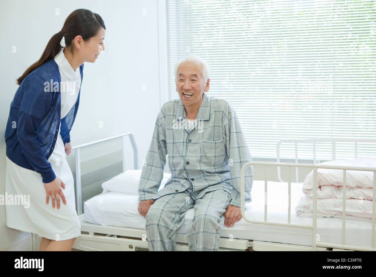 Senior man sitting on hospital bed, Kanagawa Prefecture, Honshu, Japan