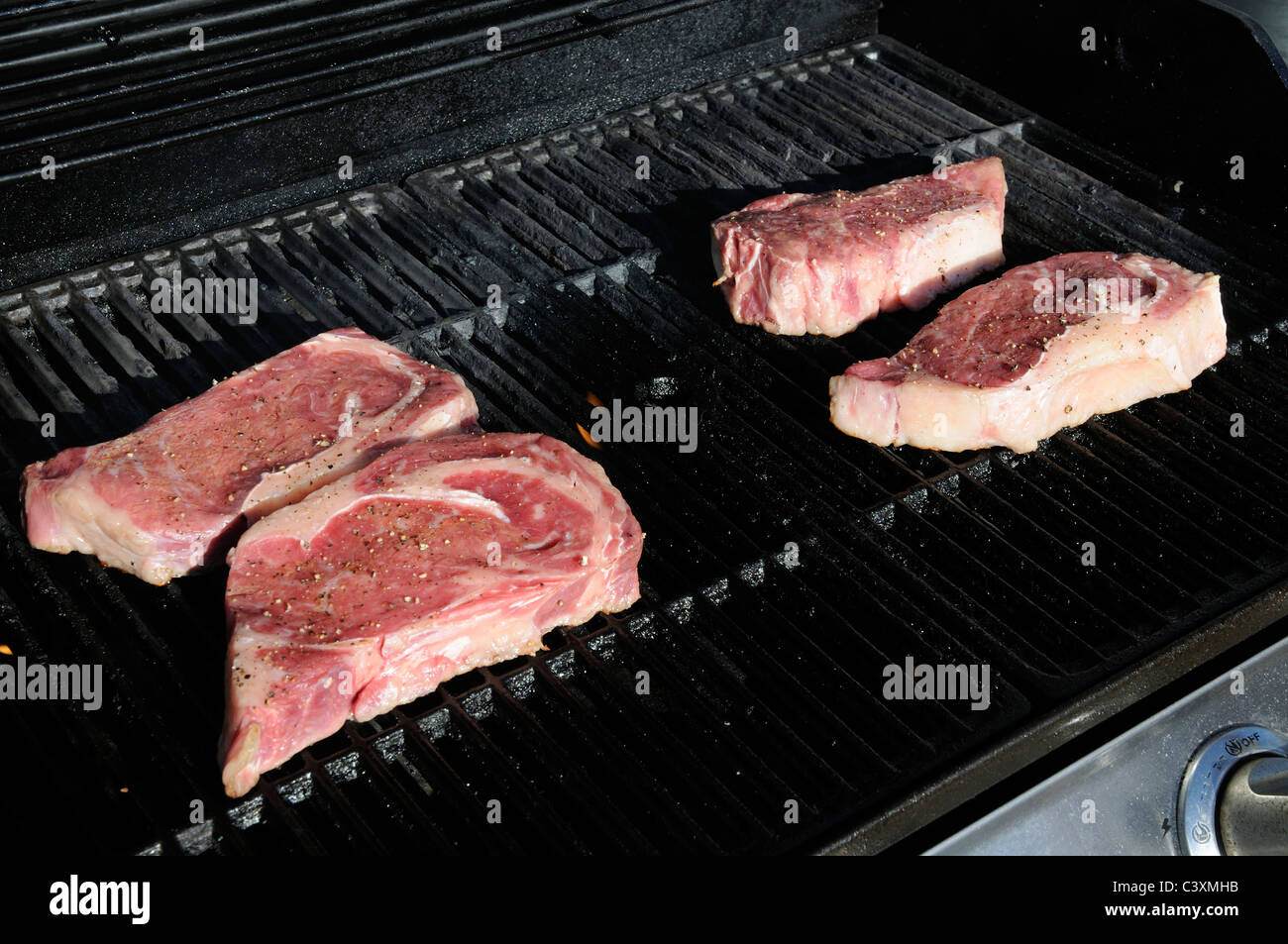 Ribeye steaks cooking on a gas barbeque Stock Photo Alamy