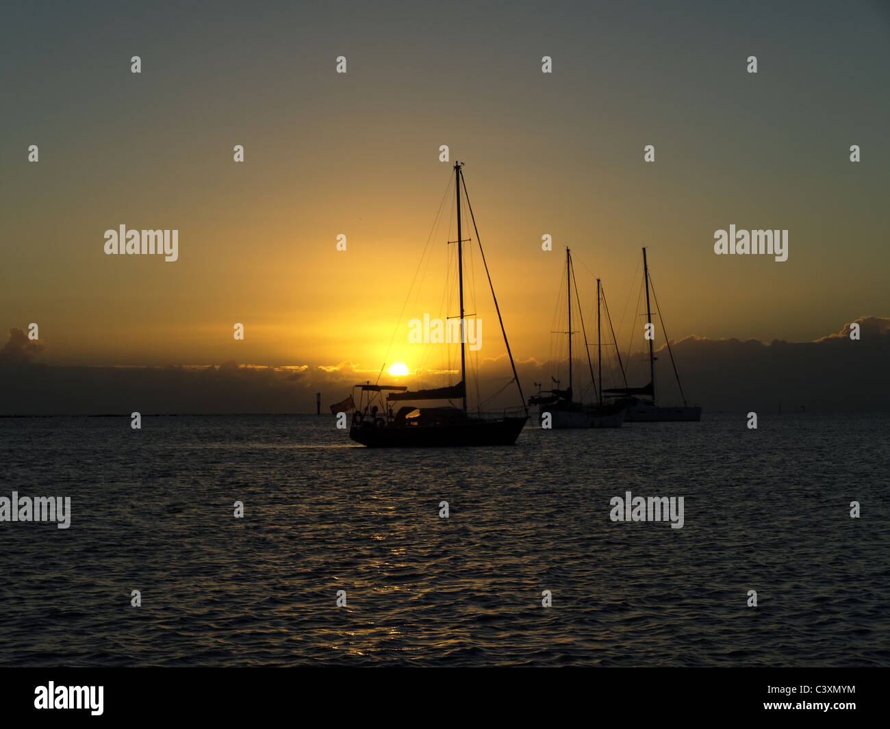 Bundaberg is the scene for a sunrise over sail boats anchored in the Burnett river Sunrise over Sailboats-Queensland-Australia Stock Photo