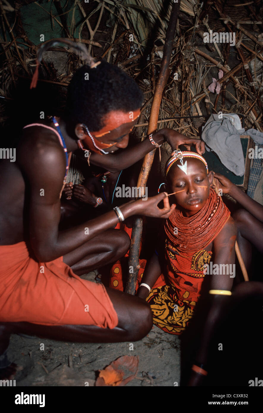El Molo Warrior paints his sister's face for a Hippopotamus tribal ceremony and dance. Lake Turkana - Kenya. Stock Photo