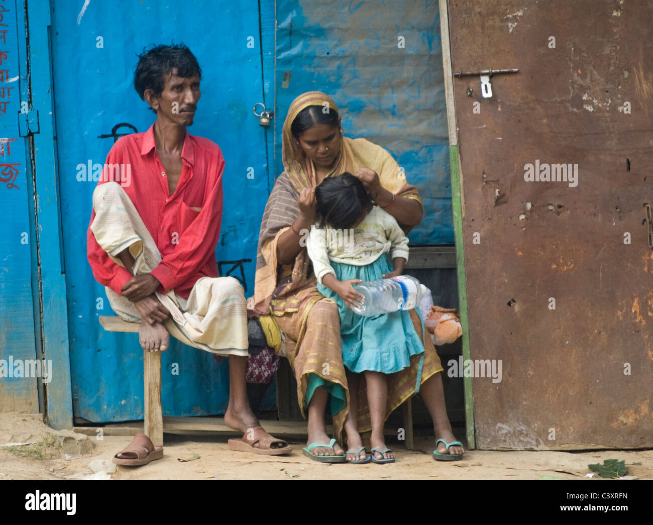 A couple and child sit in front of a home. Stock Photo