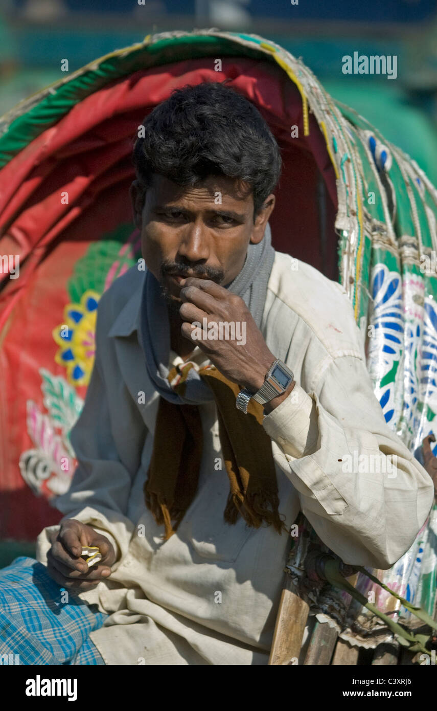 A rickshaw wallah sits by the road Stock Photo - Alamy