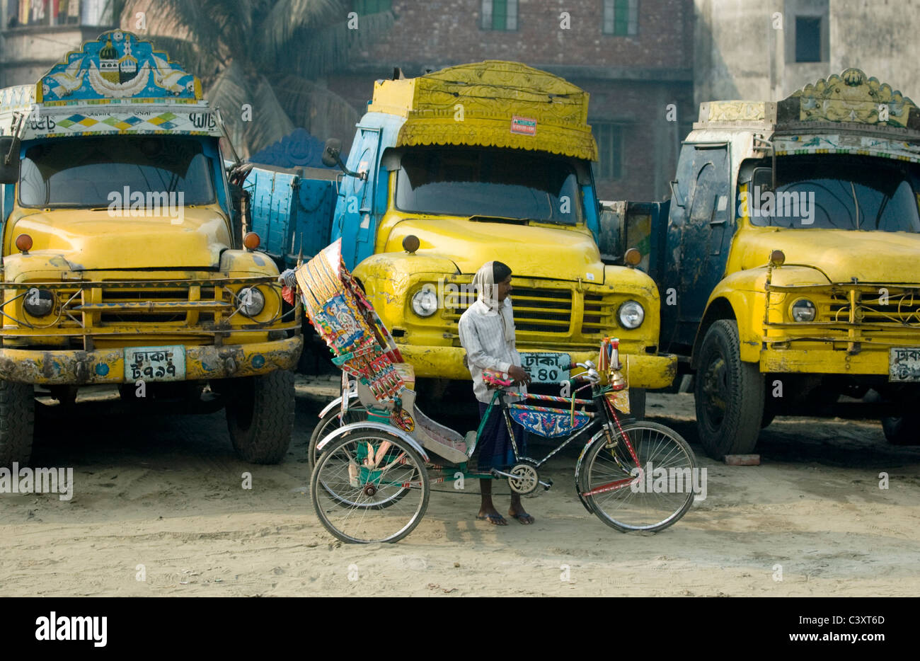 A rickshaw wallah in front of trucks Stock Photo - Alamy