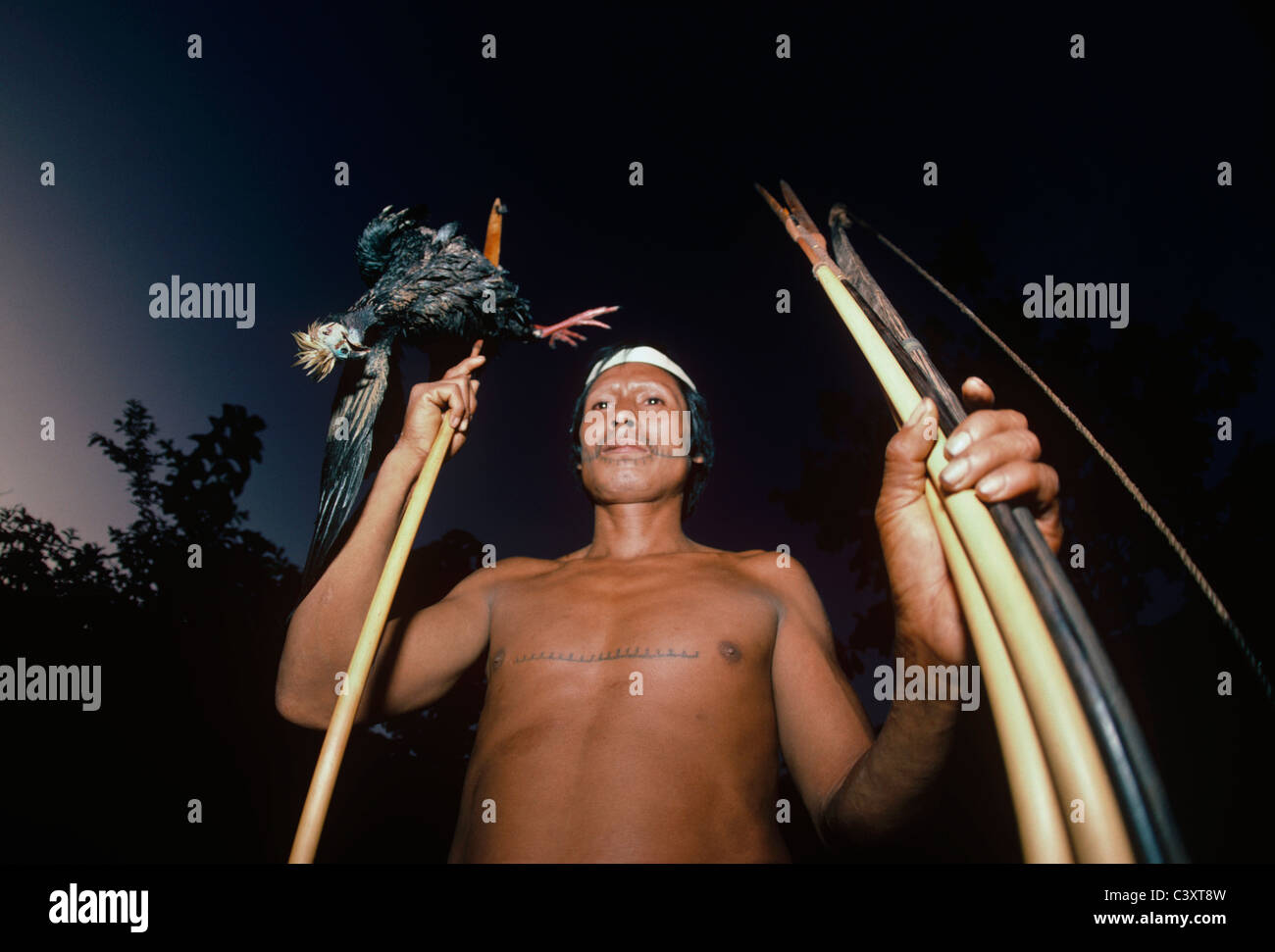 Matses tribesman with a duck (piping guan) from the Amazon killed with his bow and arrow. Matses Indians. Amazon, Peru. Stock Photo