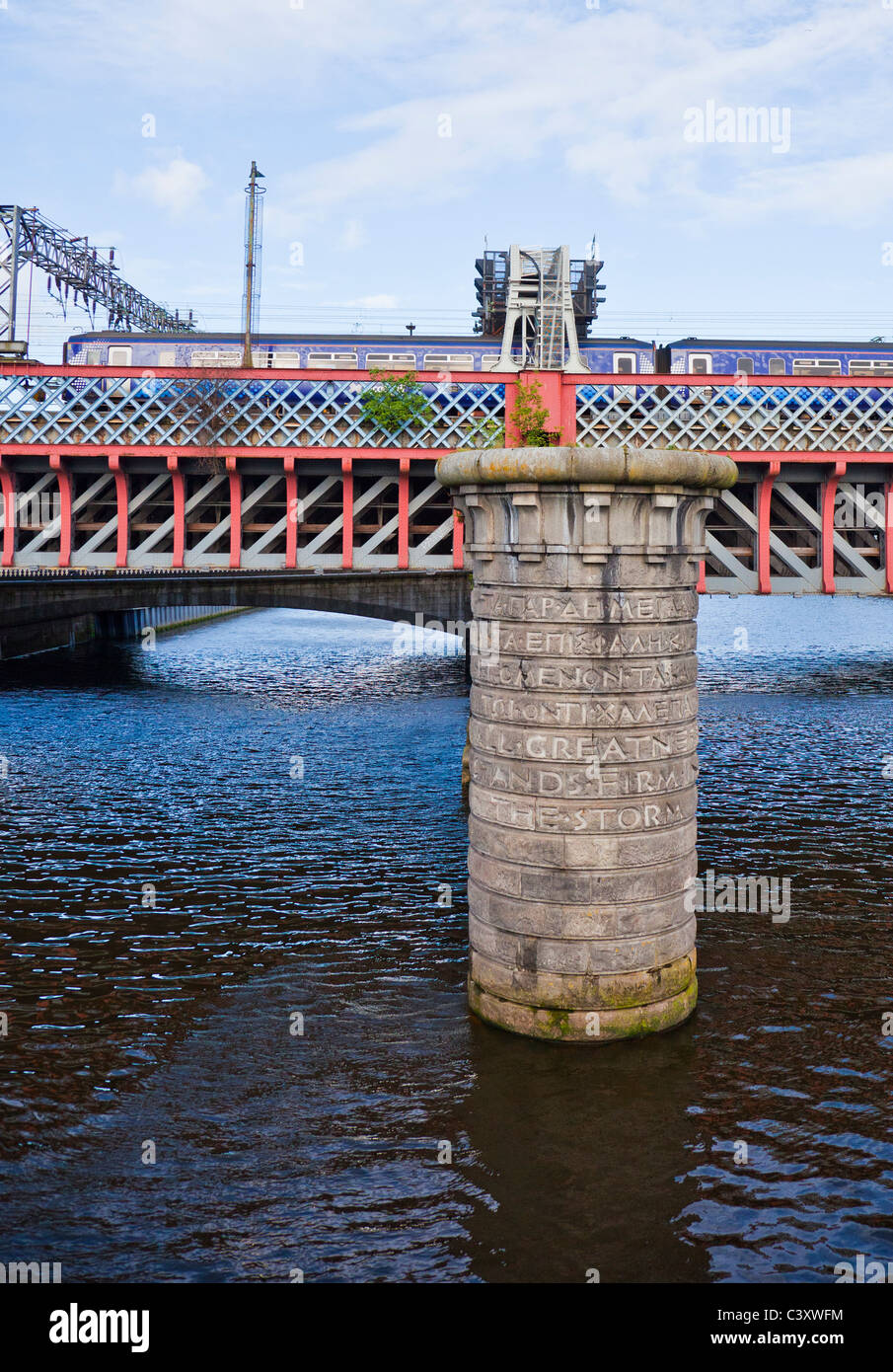 Train crossing the Second Caledonian Railway Bridge over the River Clyde in central Glasgow. Granite pier of 1st rail bridge. Stock Photo