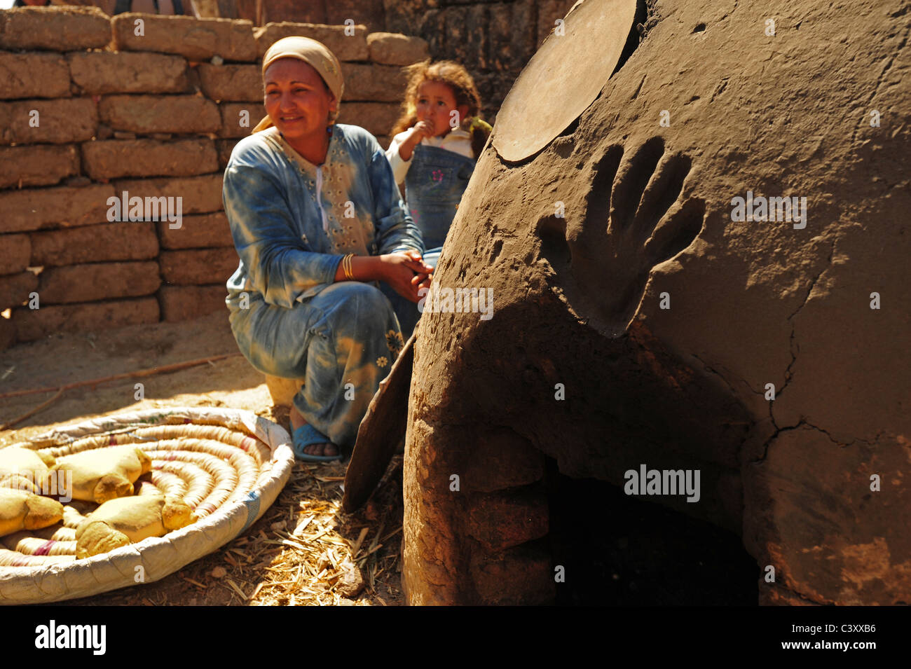 Africa Middle East Egypt Egyptian Mother and daughter making bread in an earthen oven clay outdoors in rural countryside Stock Photo