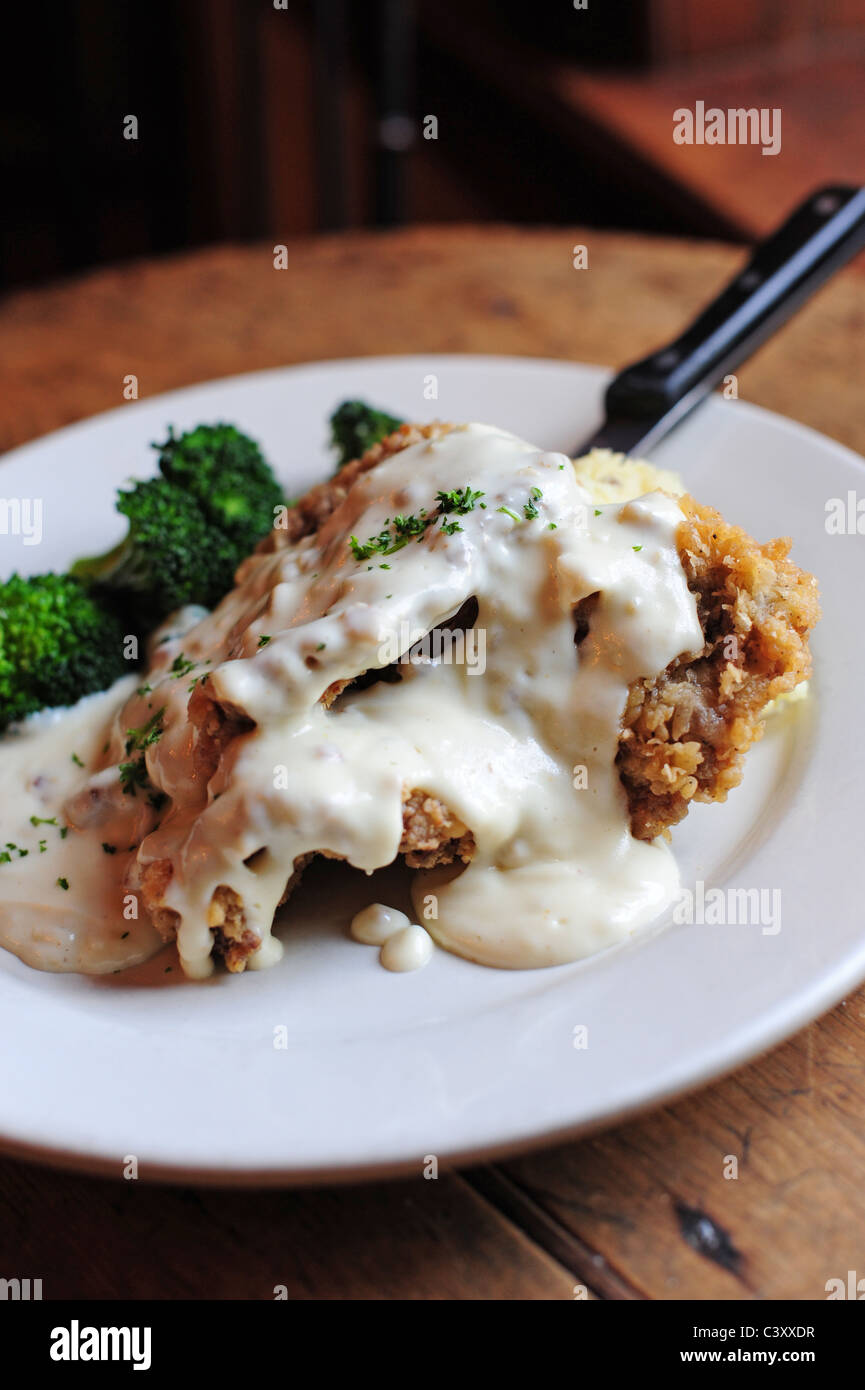 Food dining Chicken fried steak and broccoli with white gravy on top Stock Photo
