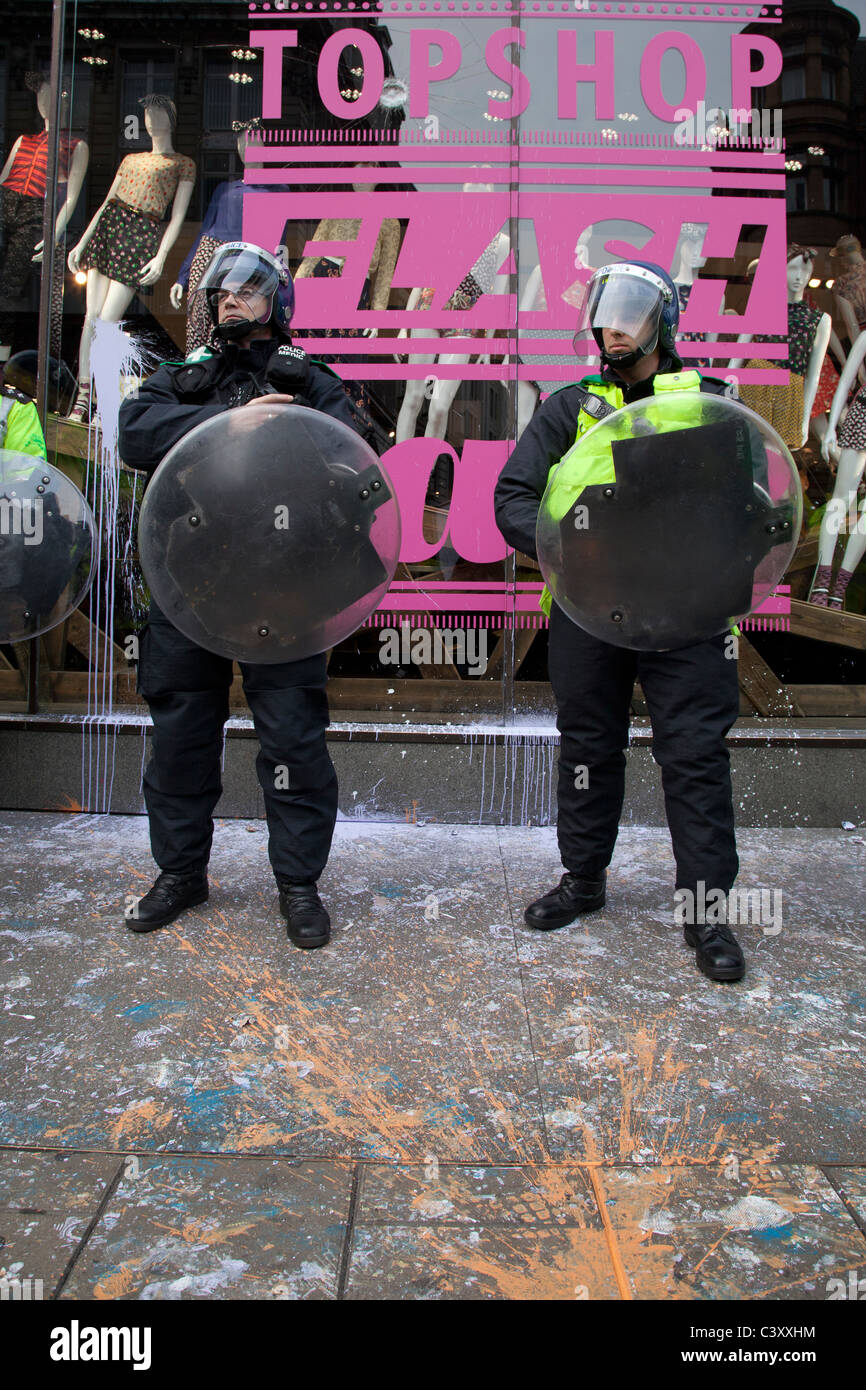Surrounded by paint splashes, Police in riot gear stand in front of a Topshop window near Oxford Circus. Stock Photo