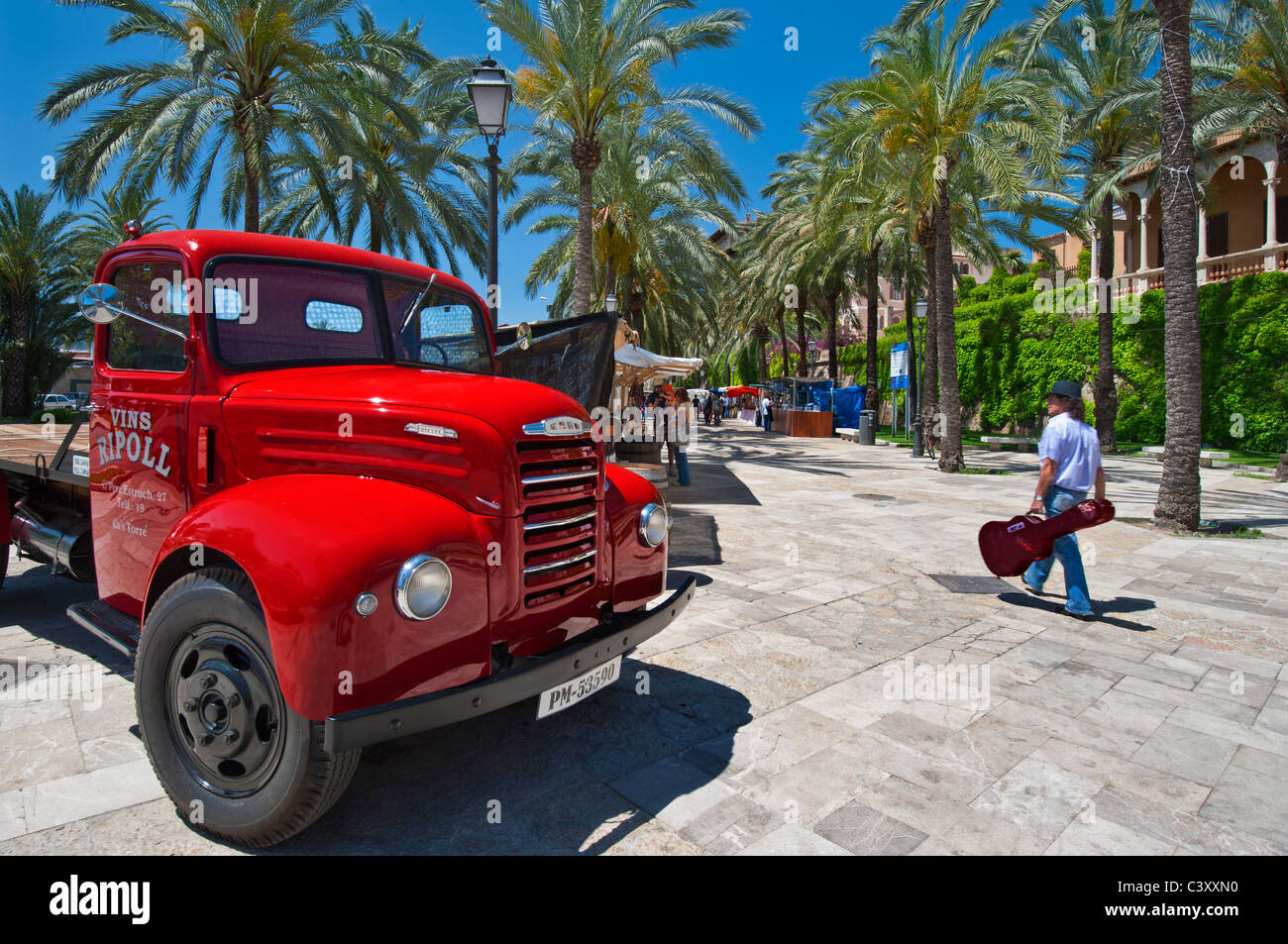 PALMA OUTDOOR MARKET STALLS Vintage Spanish red delivery lorry advertising wine market stall with man carrying Spanish guitar Palma de Mallorca Spain Stock Photo