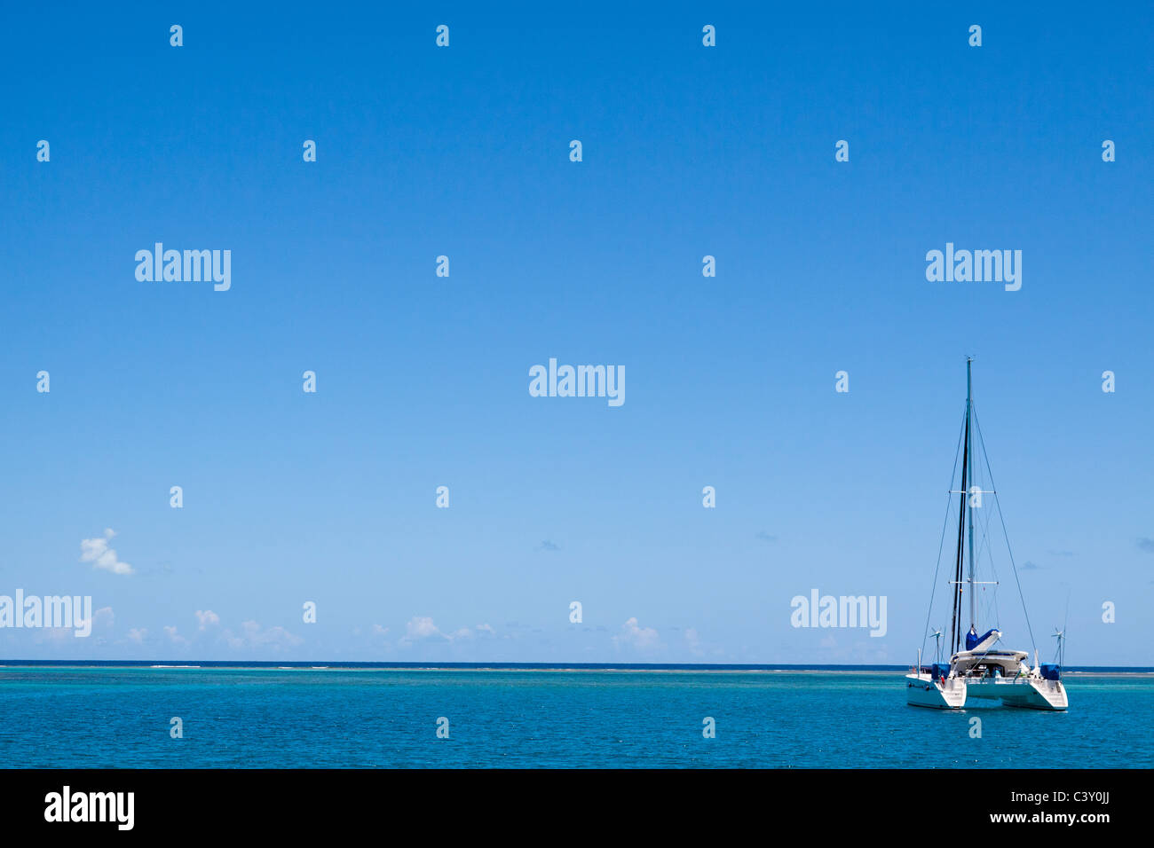 Sparse image of catamaran sailboat moored in turquoise water and blue sky in Caribbean Sea Stock Photo