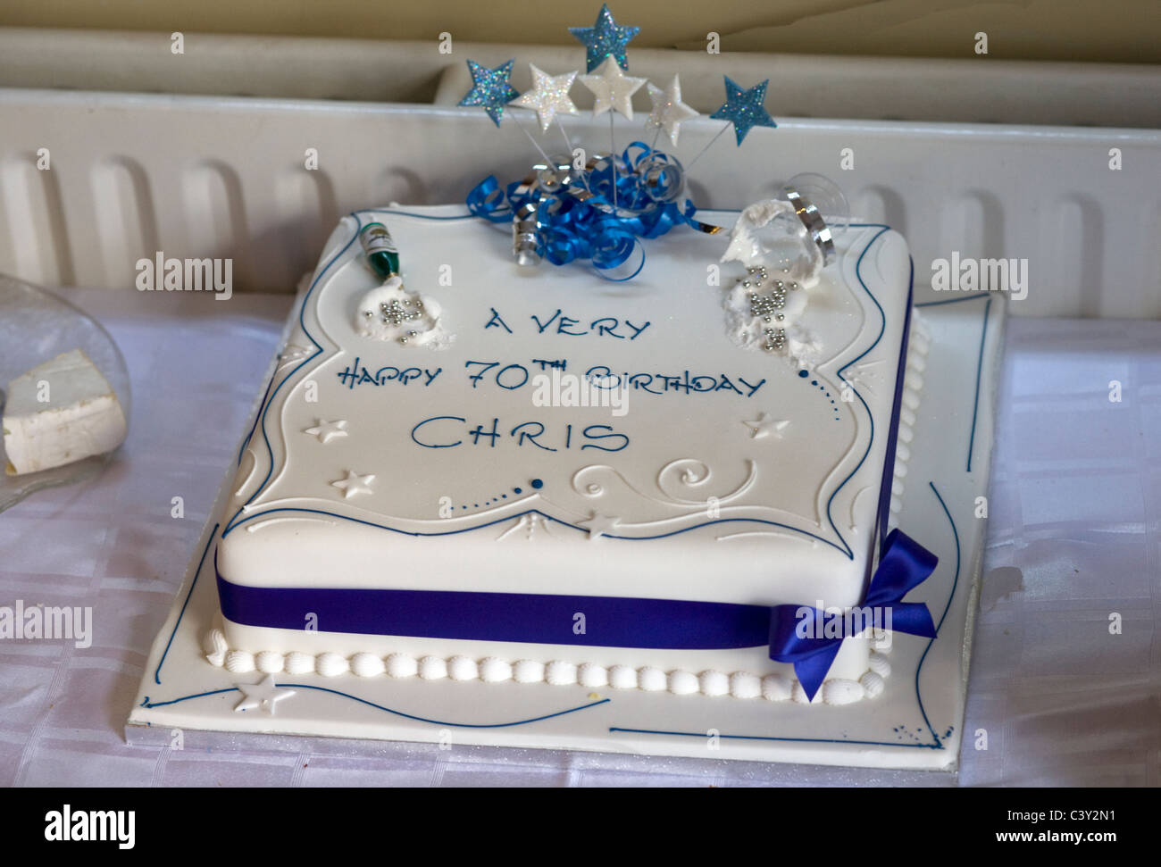 Birthday cake, with white icing and blue ribbon for a very happy 70th birthday for Chris Stock Photo