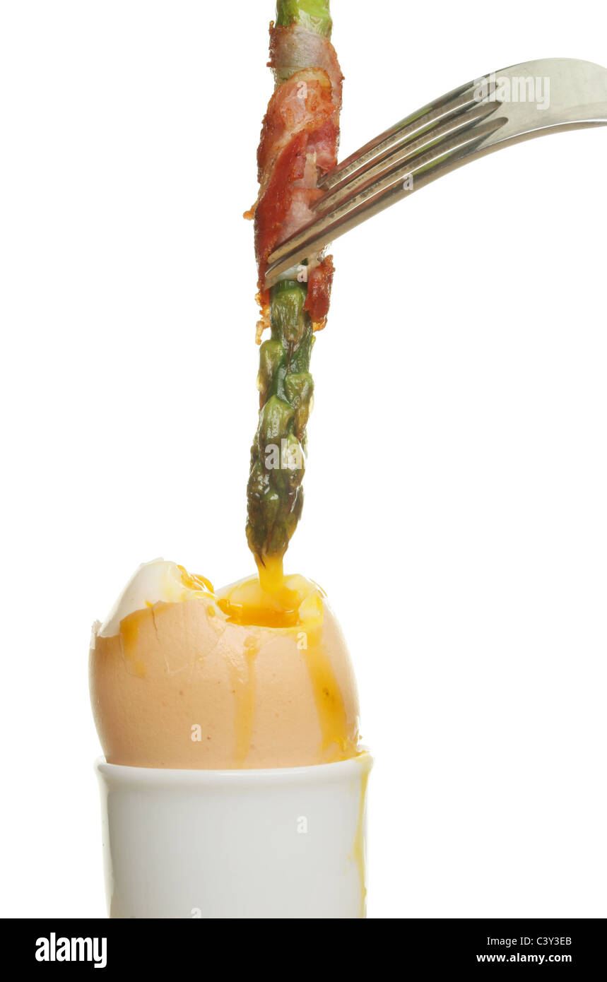 Asparagus wrapped in pancetta dipped into the yolk of a soft boiled egg Stock Photo