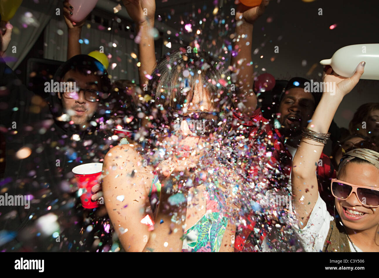 People dancing at party, woman blowing glitter Stock Photo