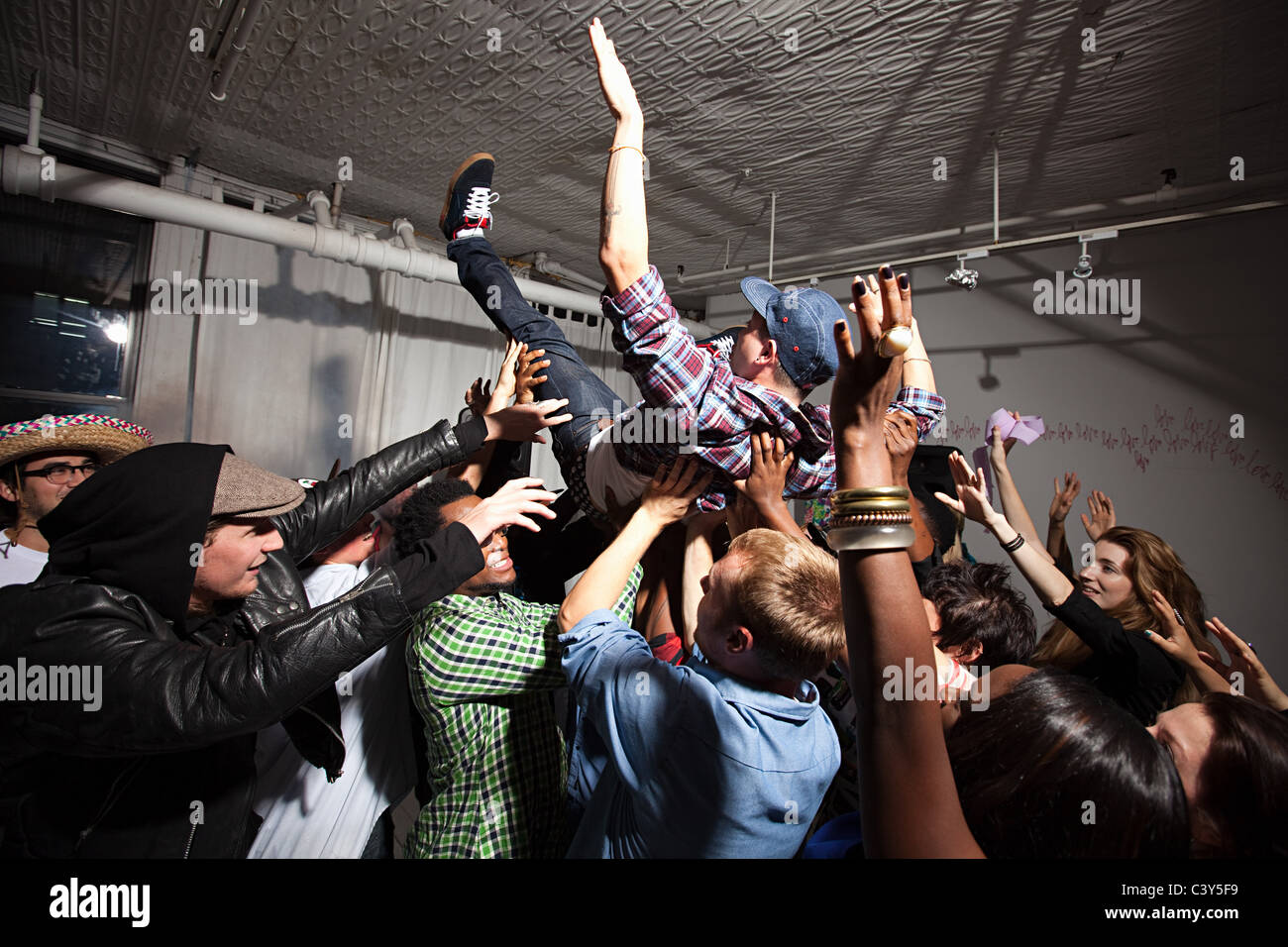 Man crowd surfing at party Stock Photo
