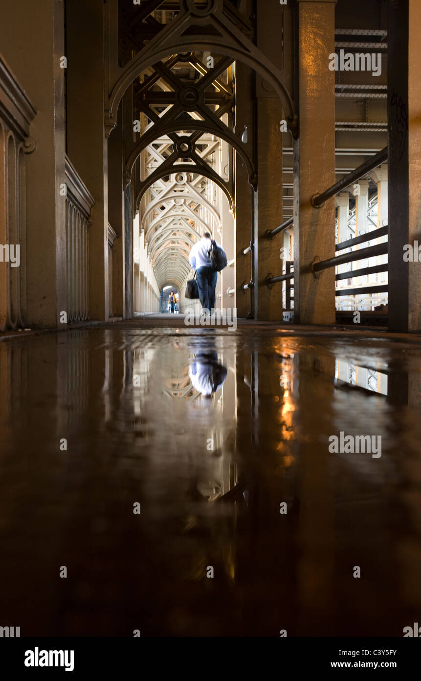 A man is reflected in a puddle on the High Level Bridge over the River Tyne linking Gateshead to Newcastle upon Tyne Stock Photo