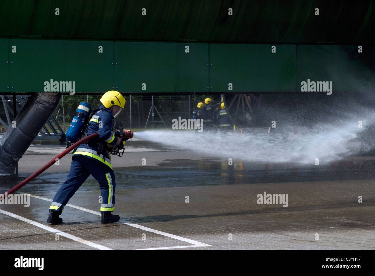 Airport firefighter using a hose during a drill Stock Photo