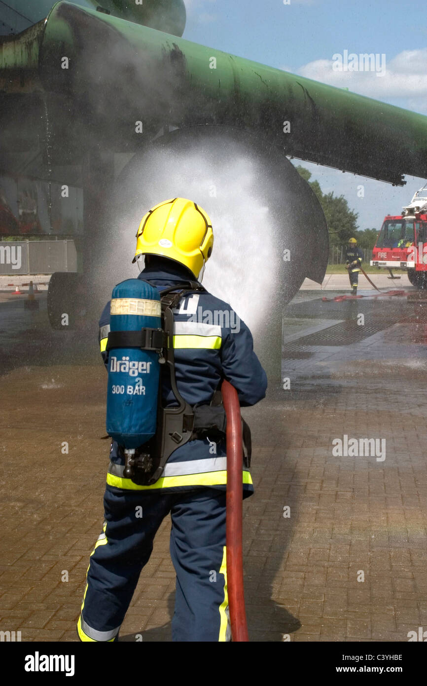 Airport firefighter tackles a simulated engine fire on an aircraft fire trainer Stock Photo