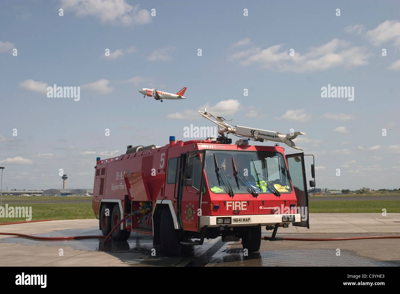 Airport fire engine with plane flying overhead Stock Photo
