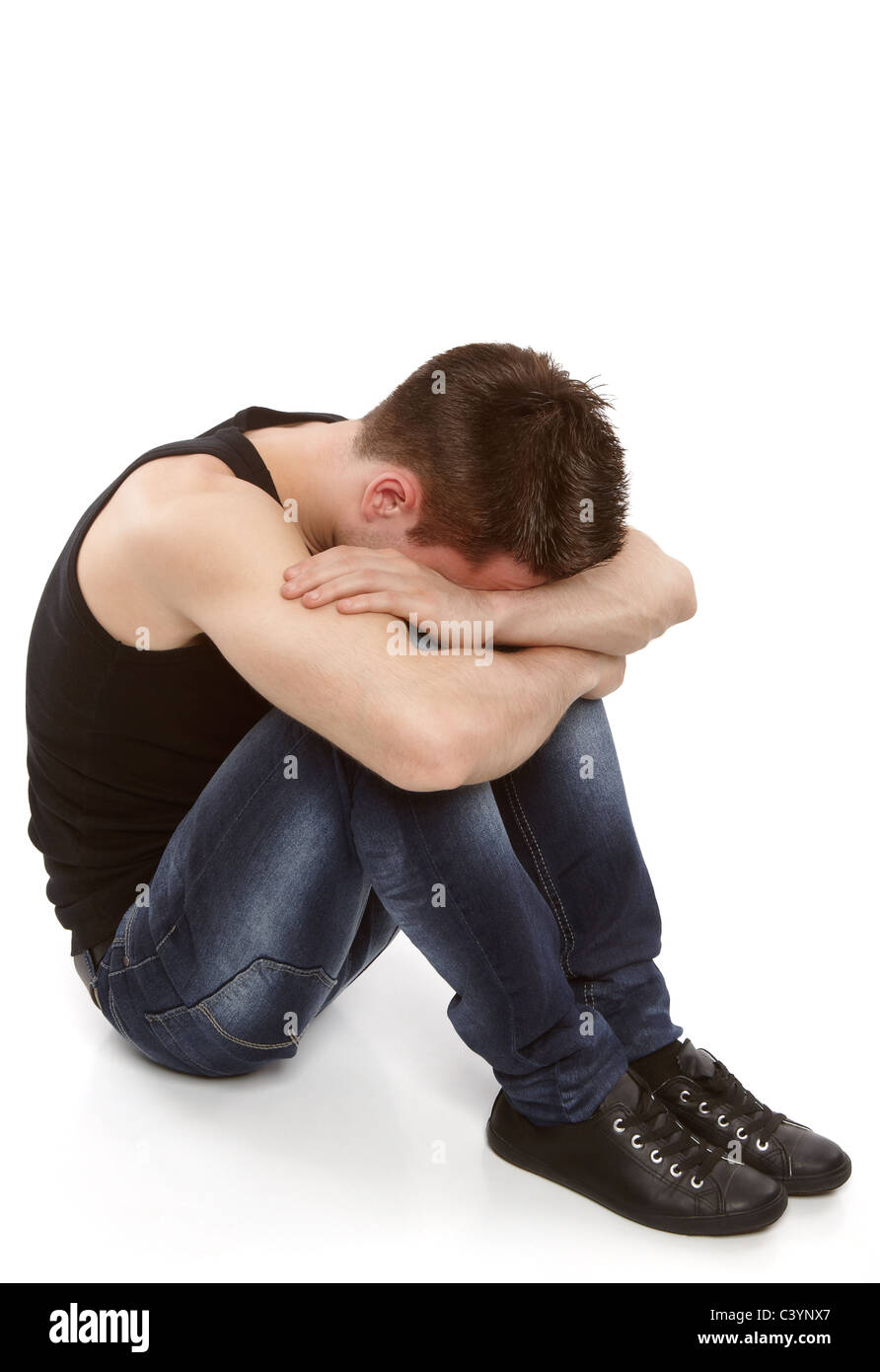 Young man thinking and hiding his face between his knees Stock Photo