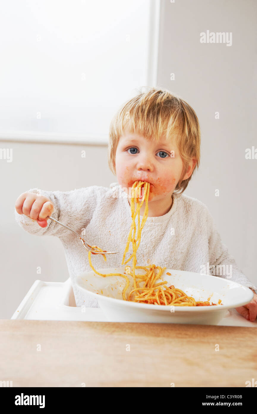 Messy baby boy eating spaghetti Stock Photo