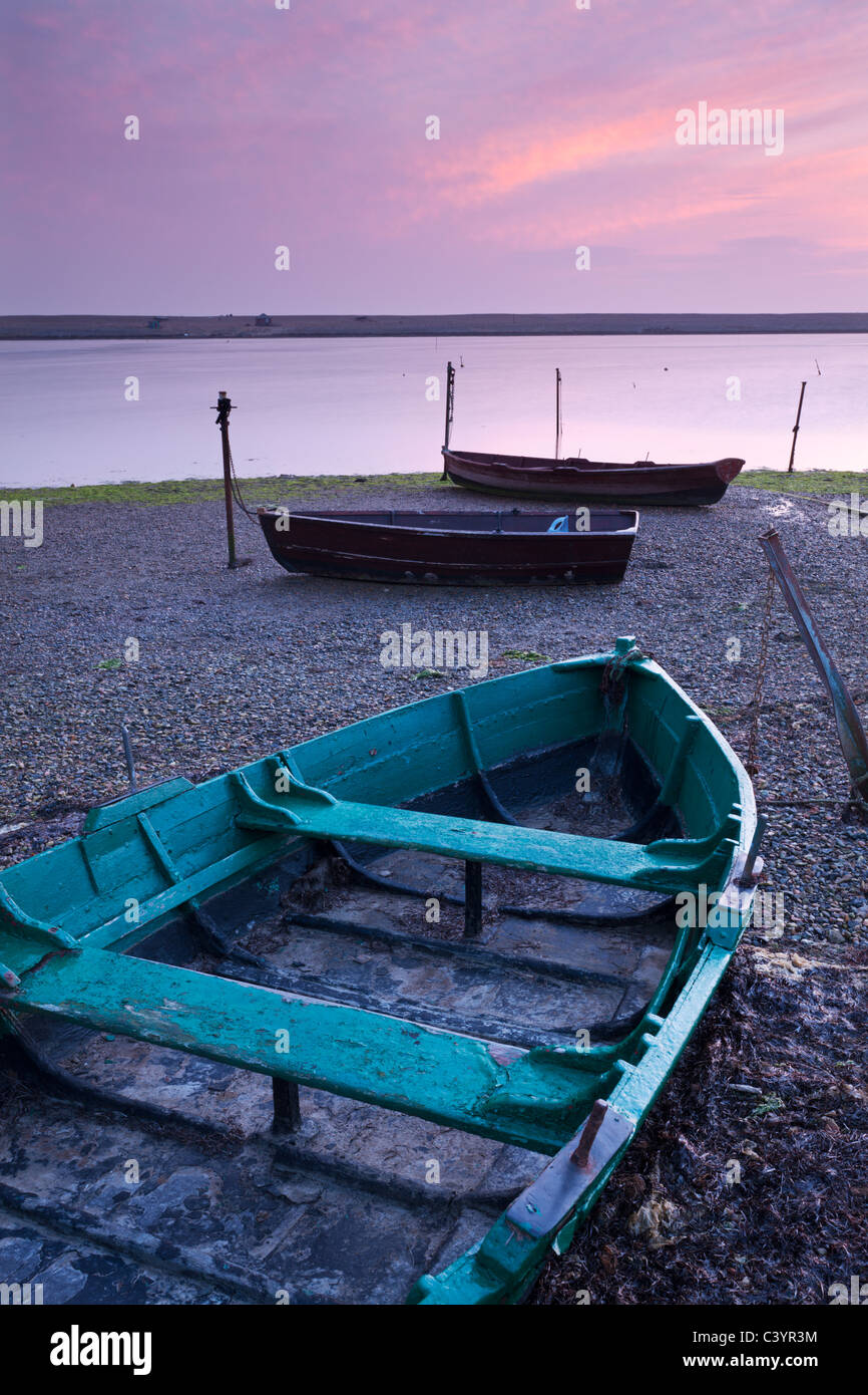 Boats at low tide on the shore of The Fleet lagoon, Chesil Beach