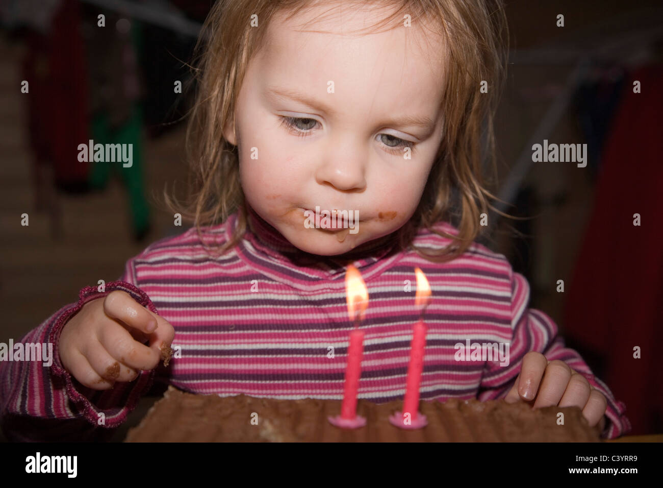 Two years old girl looking at the birthday cake with two candles Stock