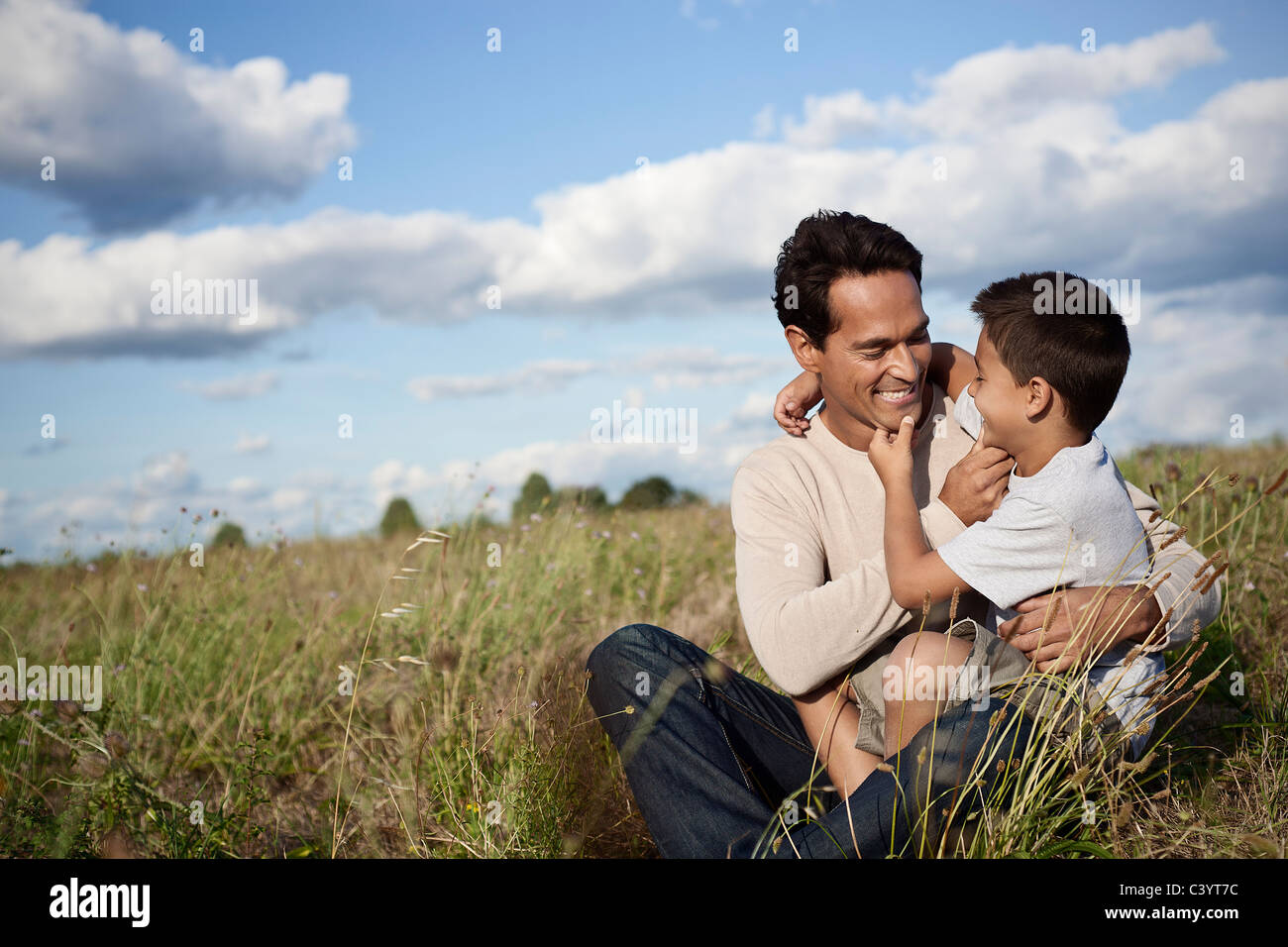 Father and son sitting in a field Stock Photo - Alamy