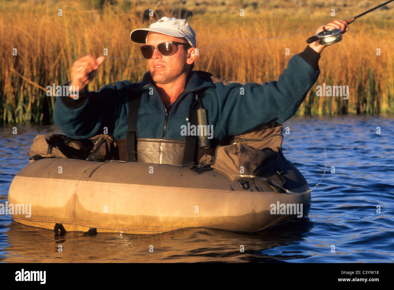 man fly fishing on river with rubber pontoon raft Stock Photo - Alamy