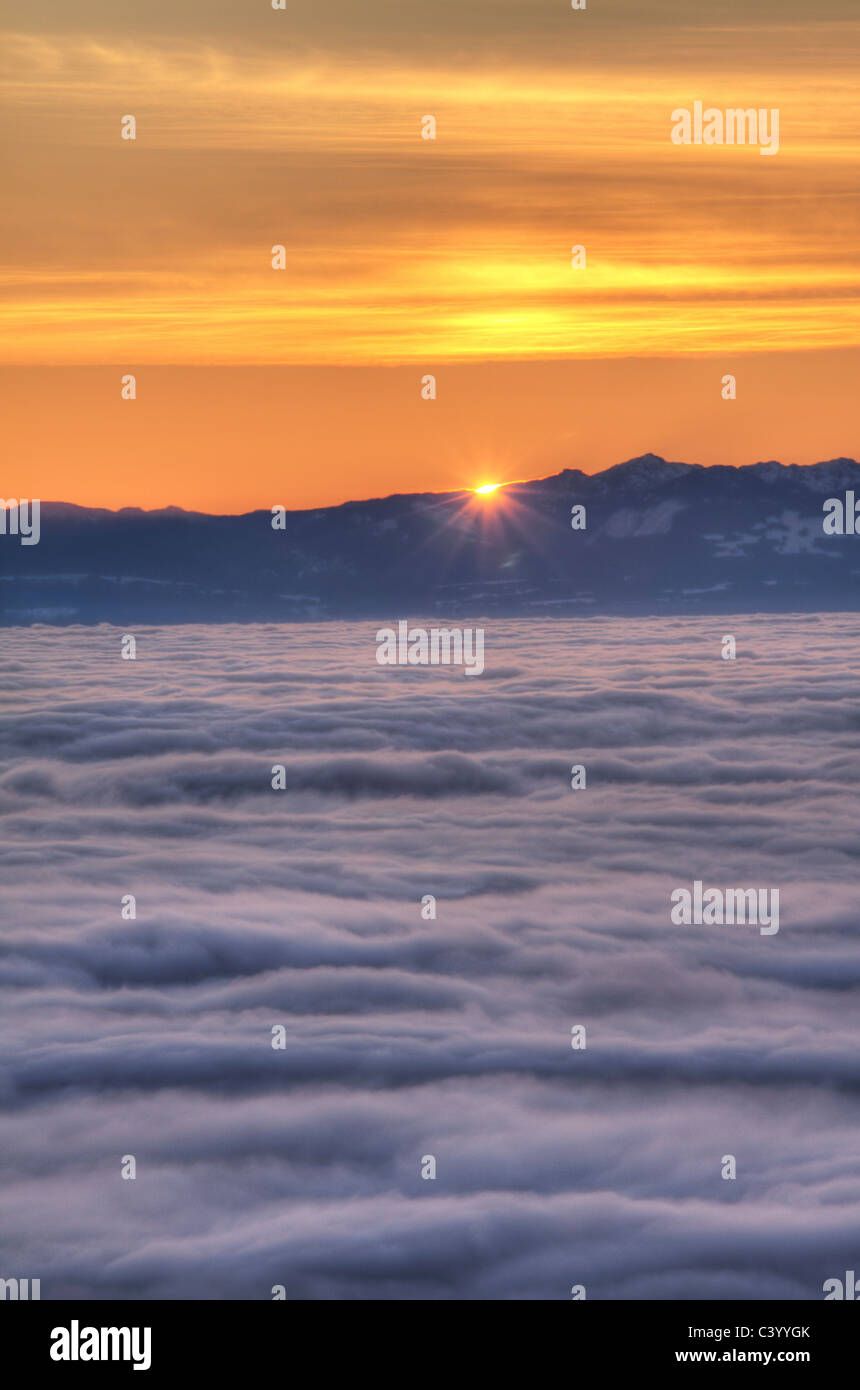 Sun sets behind Vancouver Island with fog over the Georgia Strait, as seen from Cypress Mountain in West Vancouver Stock Photo