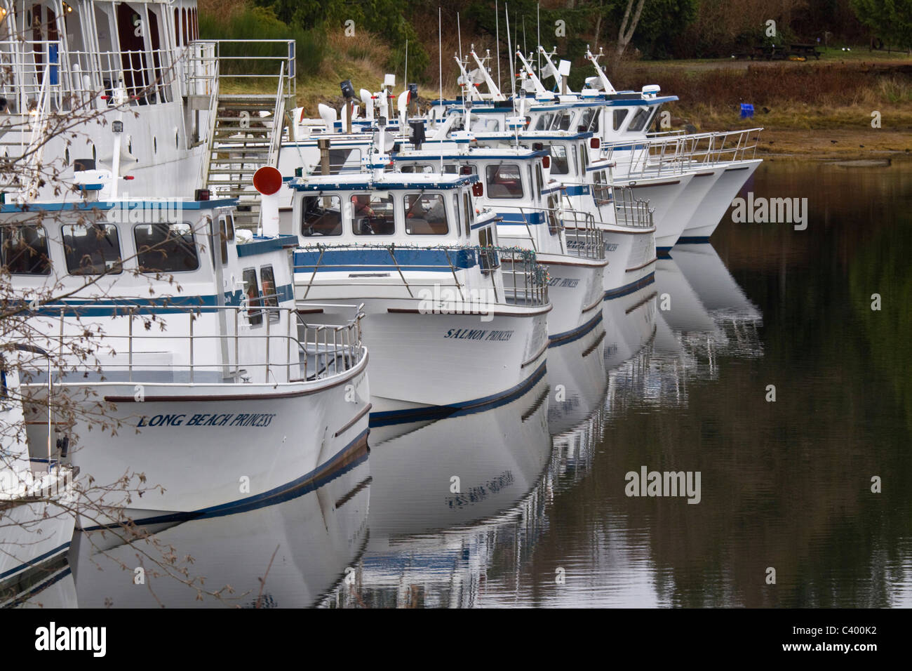 Cruise boats lined up and reflected in Ucluelet Harbour, Vancouver Island, British Columbia Stock Photo