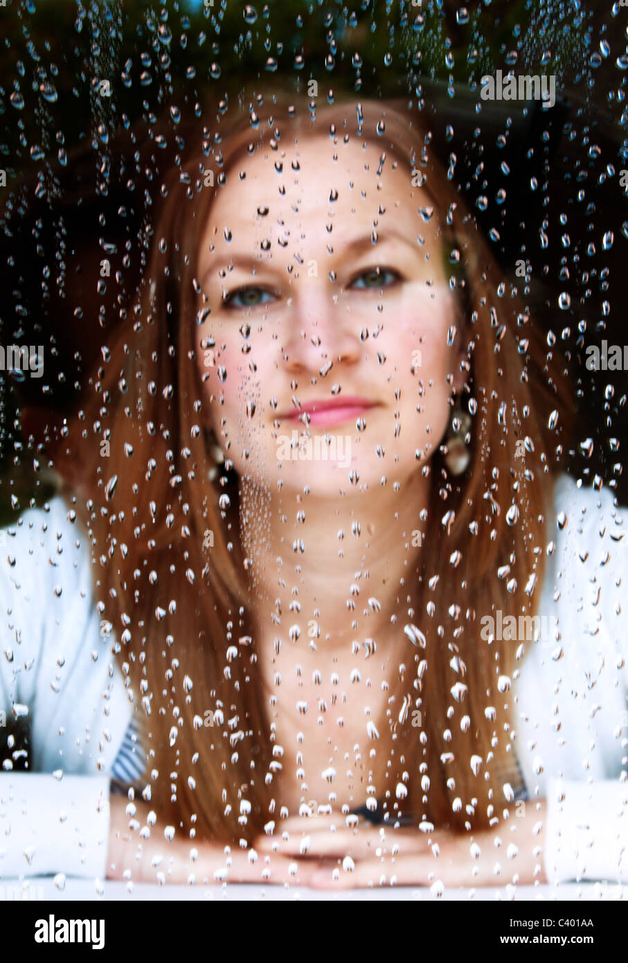 Girl looking through rain soaked window Stock Photo