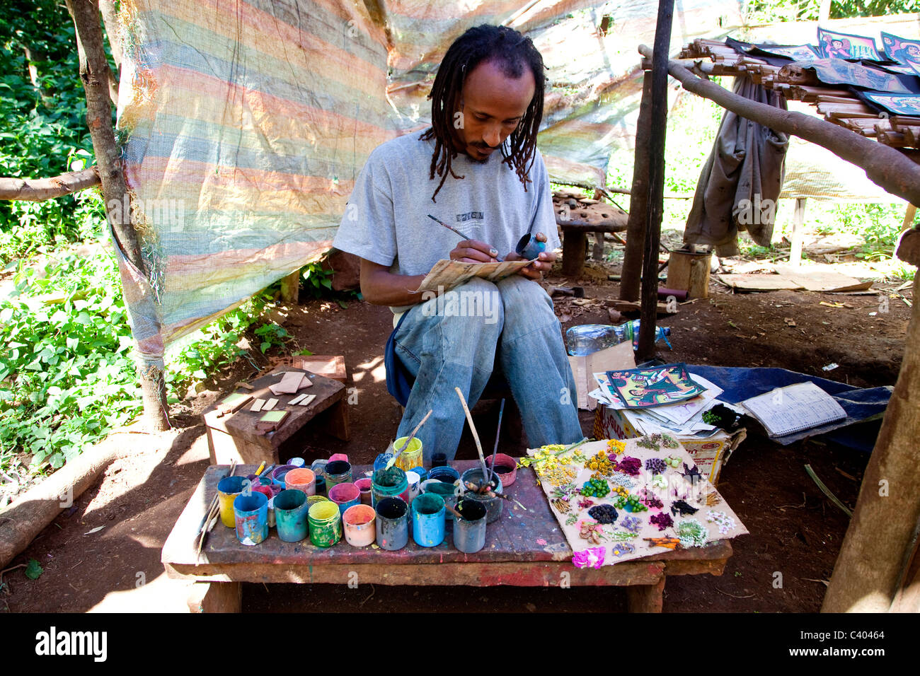 Young African artist using natural colors to paint souvenirs, Lake Tana, Ethiopia, Africa. Black man painting as hobby and job Stock Photo