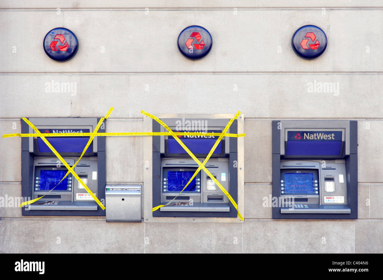 NatWest bank branch premises external outdoor atm cash machines two out of order covered in yellow tape one machine working London England UK Stock Photo