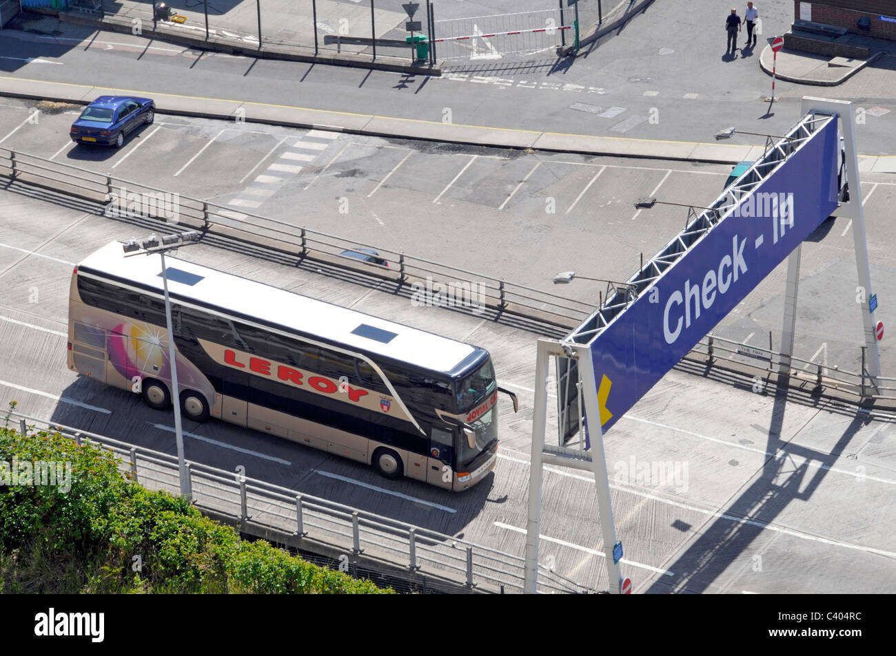 Aerial birds eye view looking down on top of double decker coach bus passing below check in gantry sign leaving Dover ferry Port Kent England UK Stock Photo