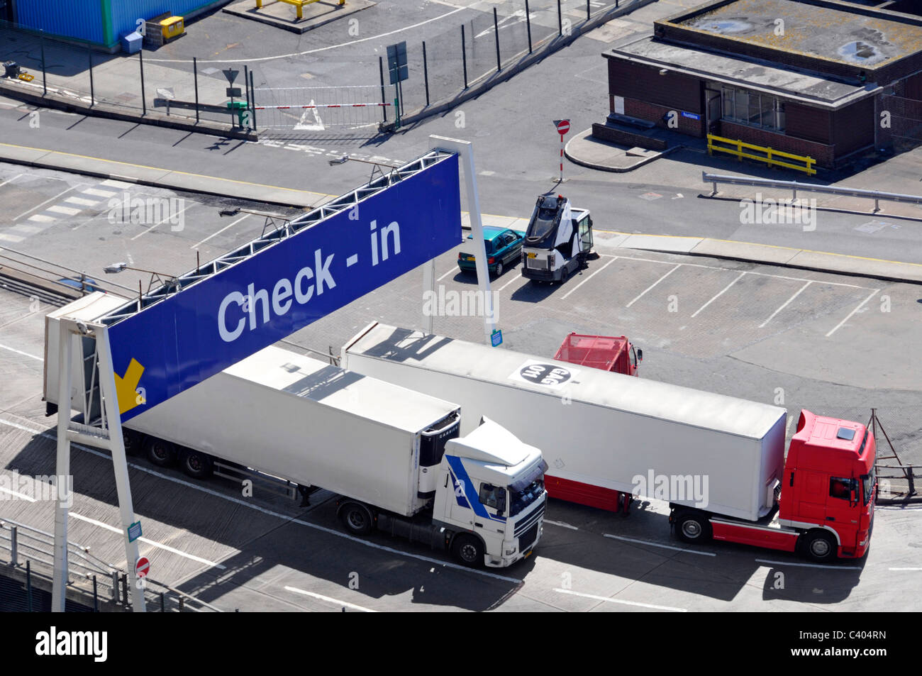 Aerial birds eye view looking down on two hgv lorry truck trailer vehicles leaving Dover ferry Port below check in lane gantry sign Kent England UK Stock Photo