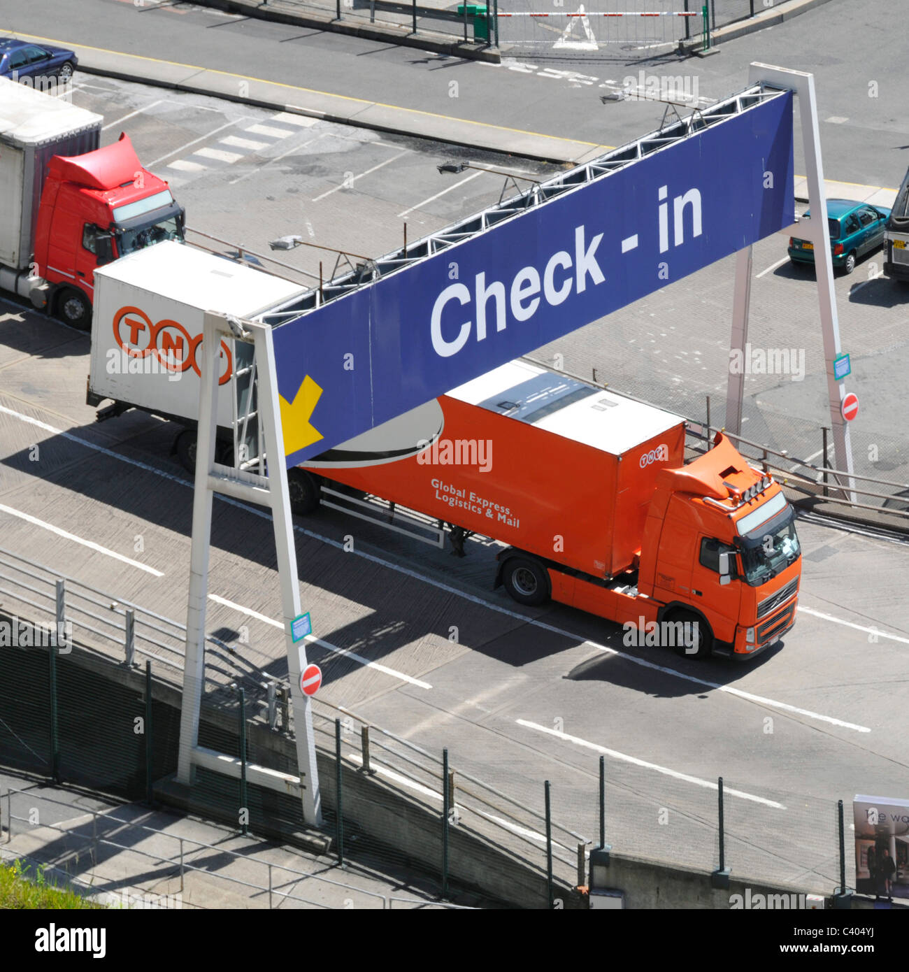 Aerial birds eye view looking down on TNT hgv lorry truck trailer vehicle leaving Dover ferry Port below check in lane gantry sign Kent England UK Stock Photo